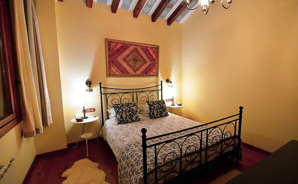 Une chambre à coucher avec un lit, deux tables de chevet, une décoration murale et une fenêtre avec des rideaux.