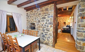 Un espace repas agrémenté d’un mur en pierre, de poutres en bois et d’un coin salon confortable.