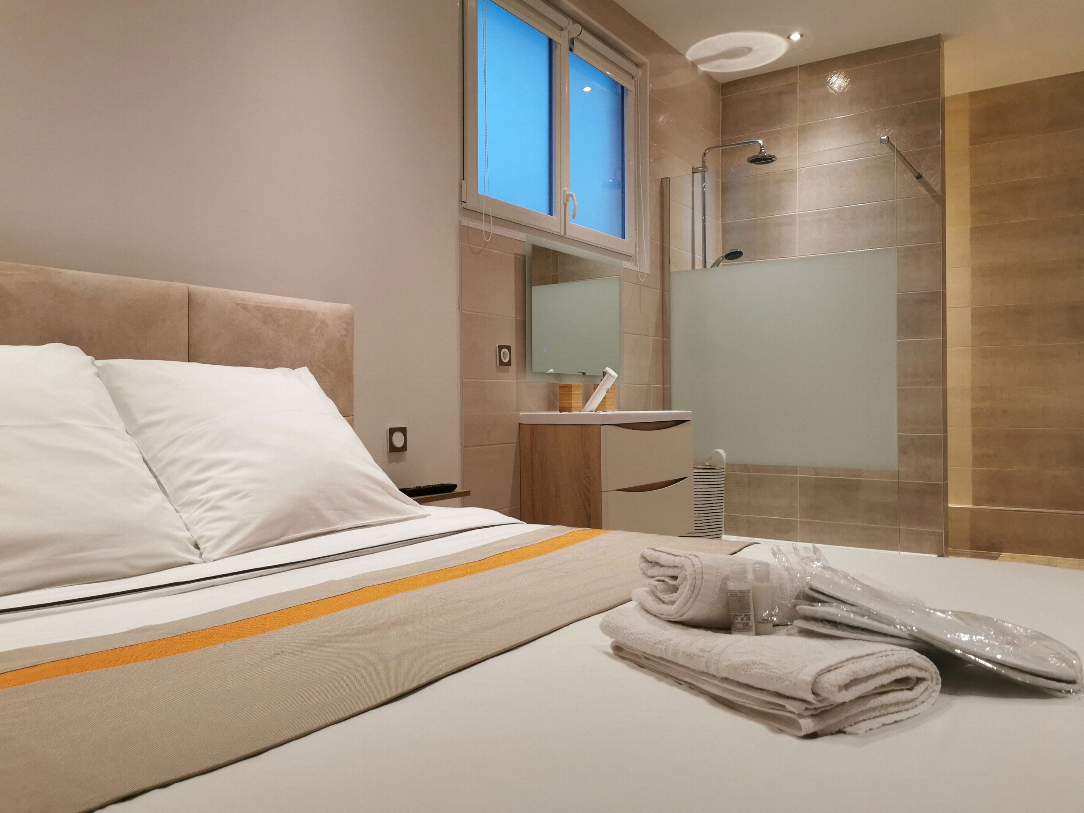 Une chambre d’hôtel moderne avec un grand lit, une douche et un petit meuble-lavabo dans la salle de bain.