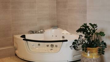 A modern bathroom with a freestanding bathtub, a potted plant, and a tiled floor.
