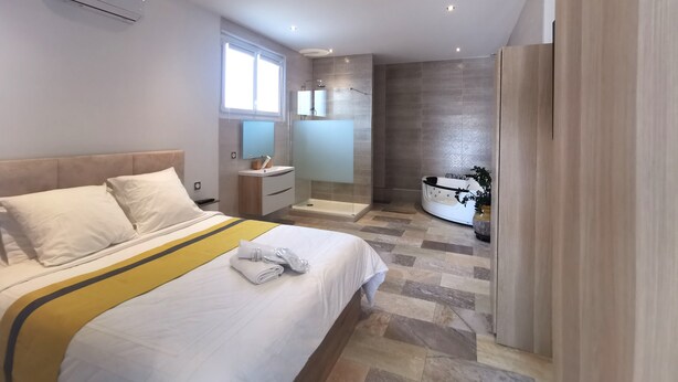 A modern hotel room with a bed, bedside table, and a bathroom with a shower and bathtub. - House (Saint Martin de Seignanx)