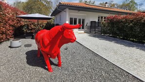 A red bull statue in a courtyard with a house in the background. - House (Saint Martin de Seignanx)