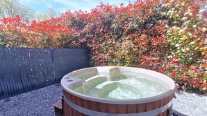 A hot tub in an outdoor setting with a wooden structure and a backdrop of colorful foliage. - House (Saint Martin de Seignanx)