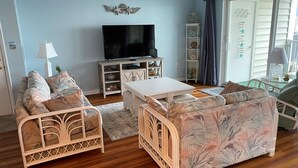 Uma sala de estar com televisão, dois sofás, uma mesa de centro e uma estante de livros.