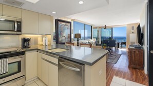 A modern kitchen with a built-in microwave, dishwasher, and a large island with a sink. - CORNER Unit with 11th Floor Waikiki Ocean, Lagoon & Marina Views! Washlet! (Honolulu)