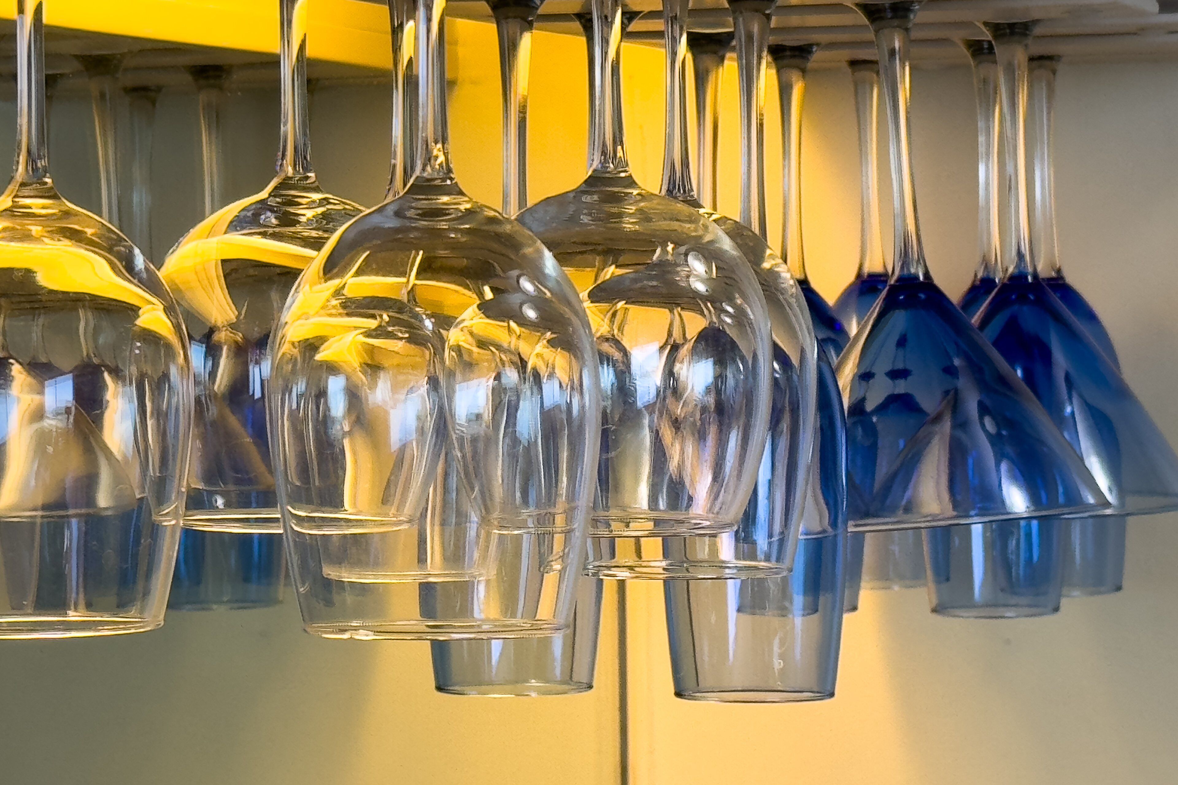 A row of wine glasses hanging from a ceiling.