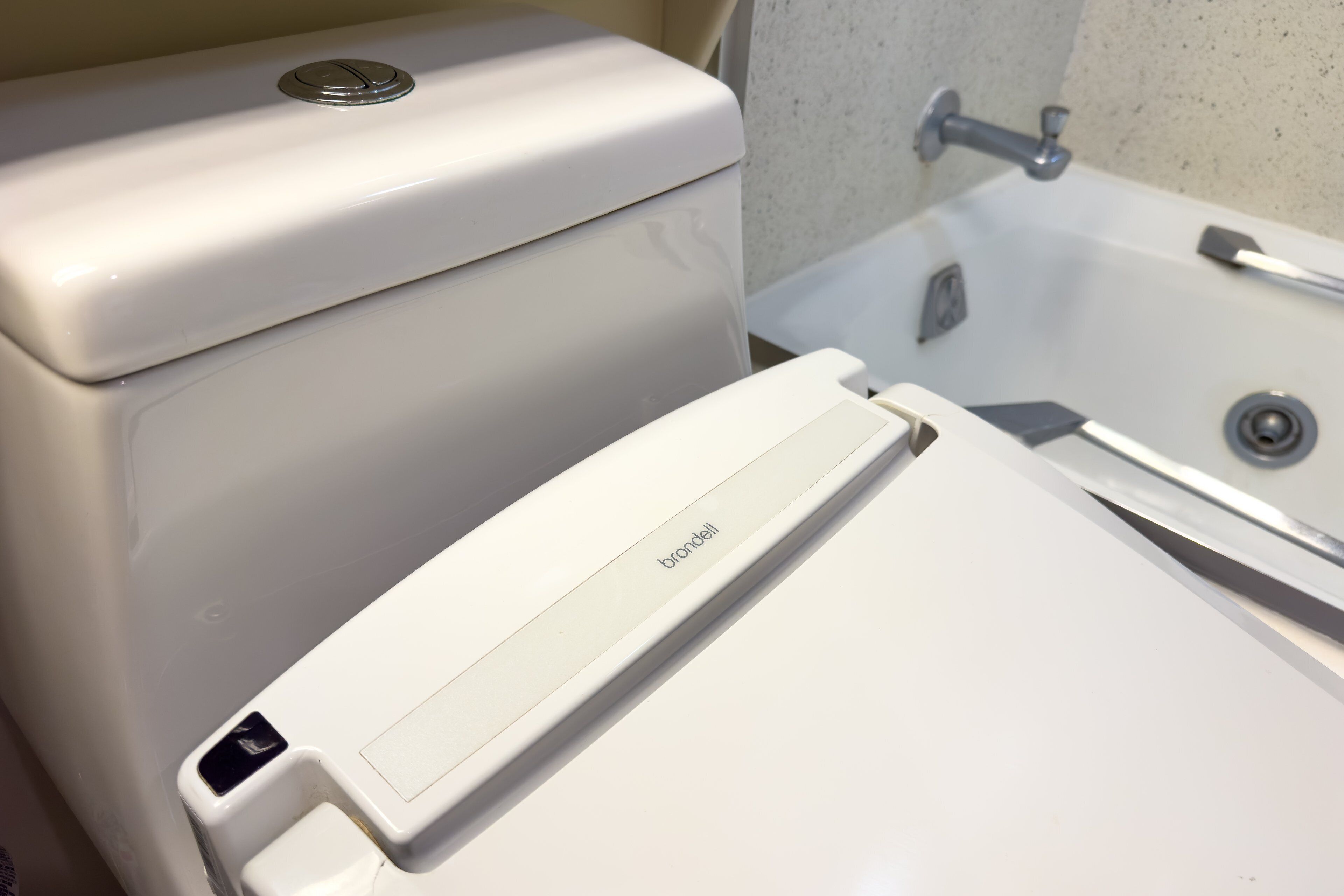 A toilet with a flush handle and a bidet attachment.
