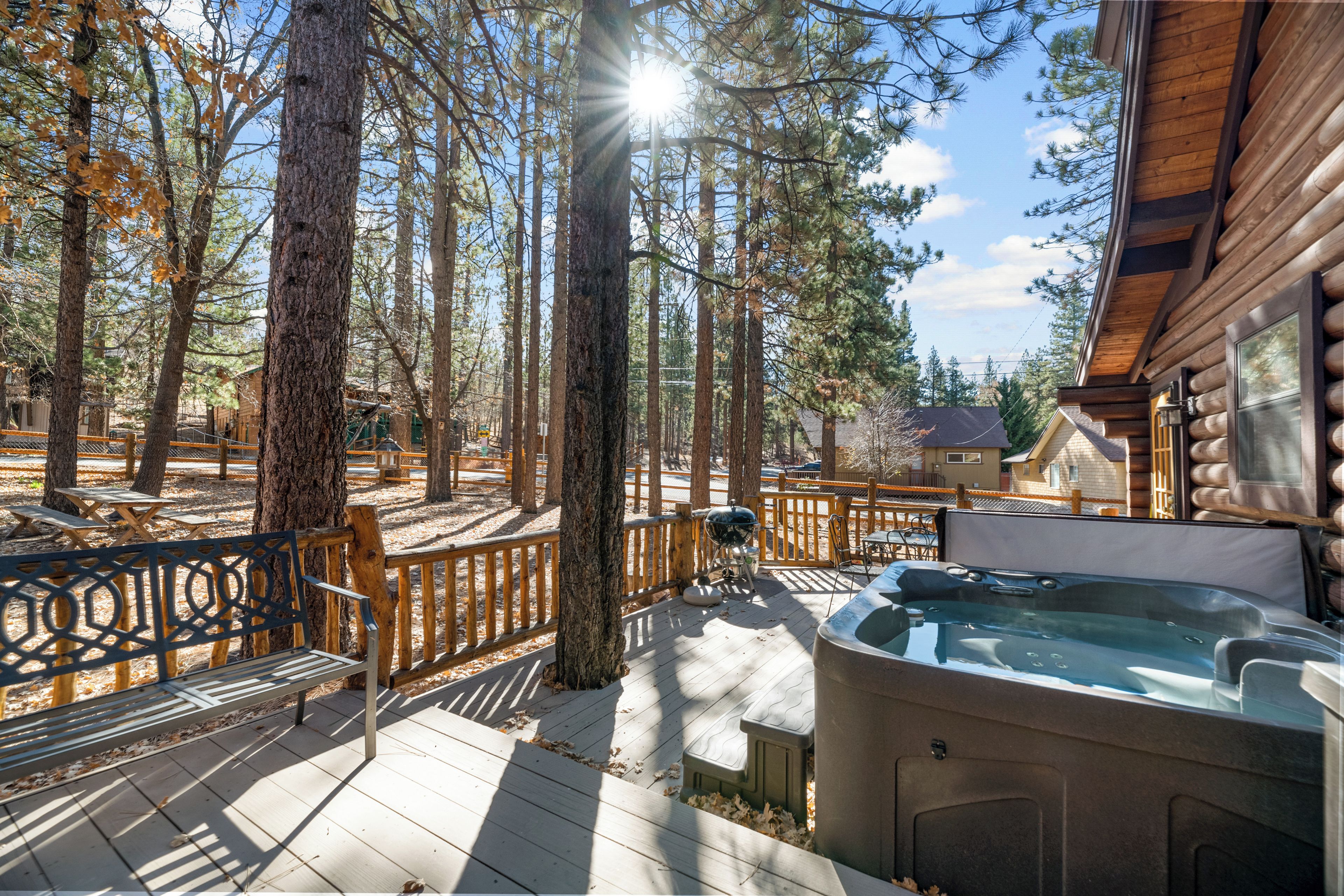 Une terrasse dotée d’un jacuzzi, d’un sol en bois et entourée d’arbres.