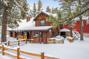 A log cabin with a wooden porch and snow-covered surroundings.