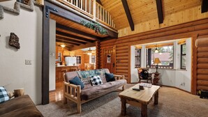 A log cabin interior with a wooden sofa, a coffee table, and a dining table. - Adorable 1,500 sq ft log cabin, HOT TUB! Close to Lake, Village, & Forest! (Big Bear Lake)