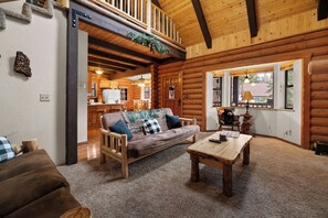A log cabin interior with a wooden sofa, a coffee table, and a dining table.