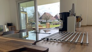 A modern kitchen with a glass door leading to a garden, a drying rack, and a set of kitchen utensils.