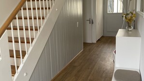 A modern interior with a wooden staircase, a white reception desk, and a door leading to another room.