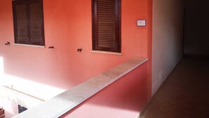 A corridor with two windows with wooden shutters, a white ledge, and a tiled floor. - Apartment in La Maddalena (La Maddalena)