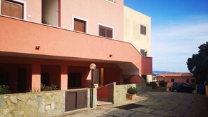 A building with a stone facade, multiple windows, and a paved courtyard. - Apartment in La Maddalena (La Maddalena)