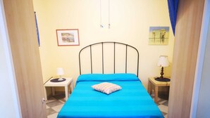 A room with a bed, two bedside tables, a wall-mounted lamp, and a framed picture. - Apartment in La Maddalena (La Maddalena)