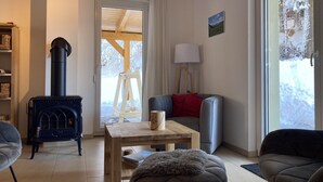 Una sala de estar acogedora con una estufa de leña, una mesa de madera, un sofá y una lámpara.