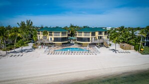 Une propriété située en bord de mer, dotée d’une piscine, de plusieurs balcons et d’une plage de sable.