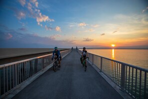 A bridge with two cyclists riding towards a sunset over a body of water. - TF Pool Beach Kitchen Sleep 6, Hot Tub W&D Marina WiFi Parking (Marathon)