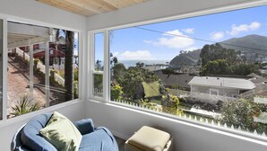 A room with a large window offering a view of a residential area and a mountain. - 124H Unit 2: Cozy 2 Bedroom Unit, Stunning Views, BBQ, GOLF CART (Avalon)