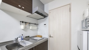 Una cocina moderna con encimeras de acero inoxidable, un lavaplatos empotrado, un microondas y un refrigerador.