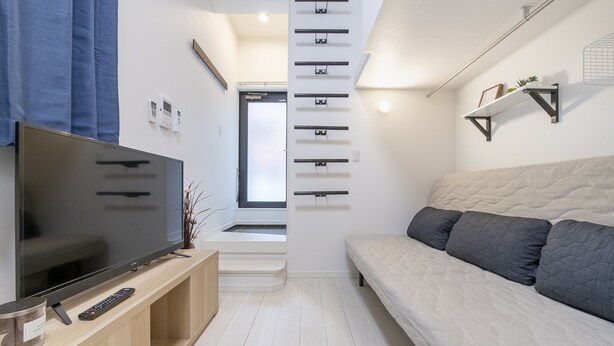 Una sala de estar moderna con un televisor de pantalla plana, un sofá, una mesa de centro y una escalera que sube a un nivel superior.