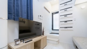 Una sala de estar moderna con un televisor de pantalla plana sobre un pedestal de madera, un control remoto y un frasco decorativo.