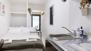 Una habitación de hotel con cama, mesita de noche, lavamanos y espejo.