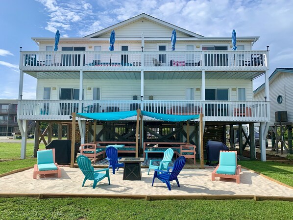 A two-story building with a balcony, outdoor seating area with chairs and a table, and a covered patio.