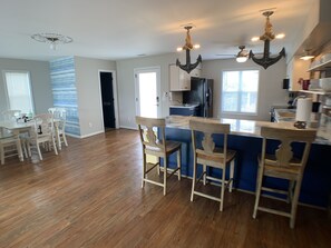 A spacious kitchen with a central island, wooden chairs, and a dining area with a white table and chairs.