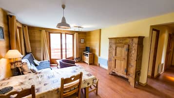 Cozy room with a bed, dining table, and TV, set amidst large windows with curtains.