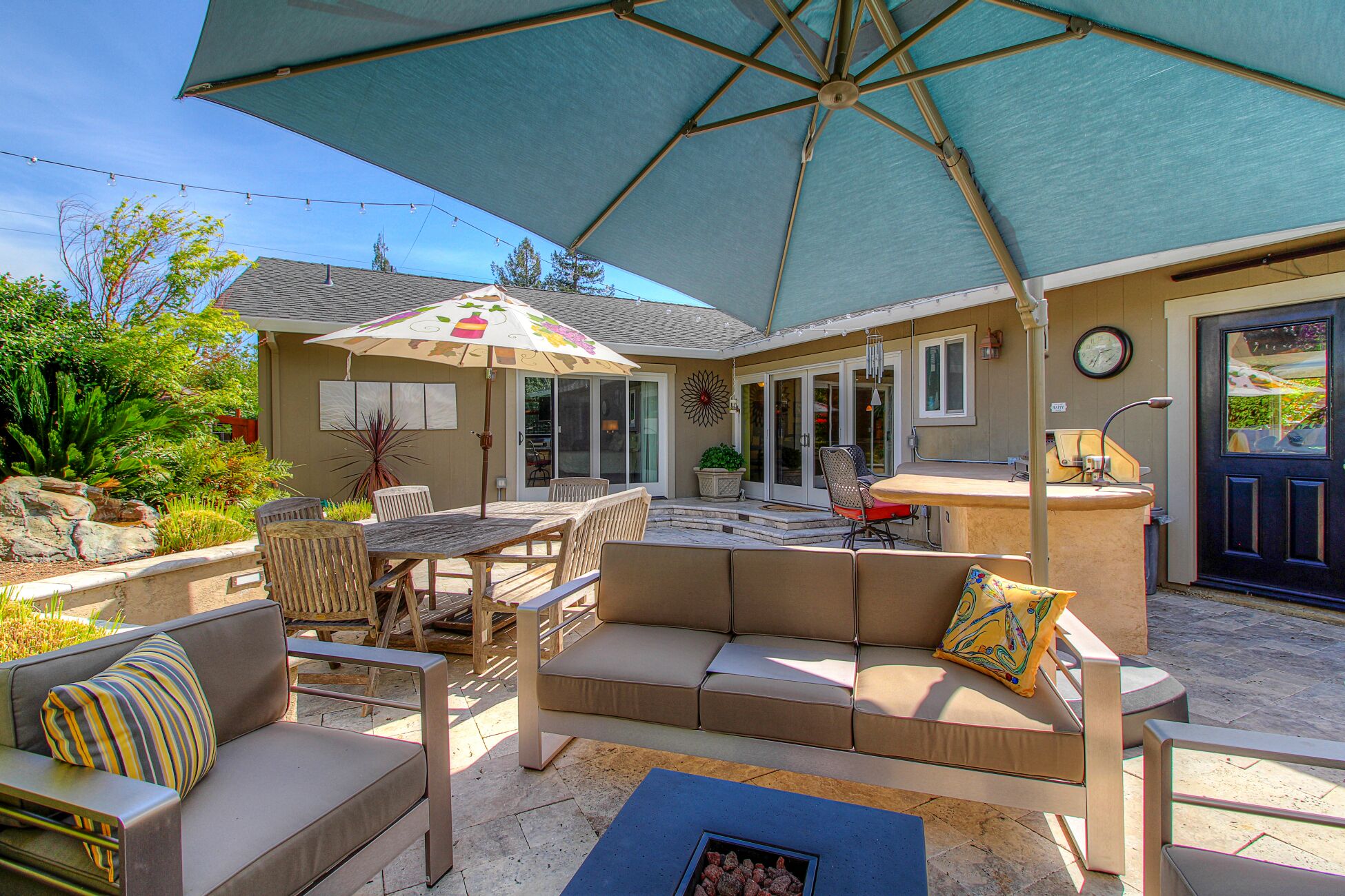 An outdoor patio with a table and chairs, a sofa, and an umbrella.