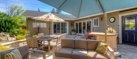 An outdoor patio with a table and chairs, a sofa, and an umbrella.