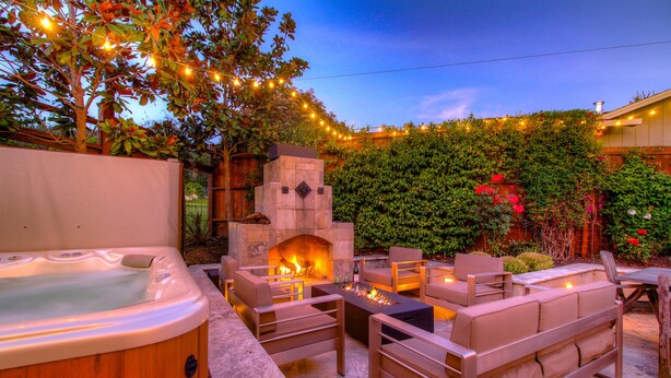 An outdoor patio with a stone fireplace, seating area, and string lights. - Perfect for Wine Country Vacation Living and Entertaining (Santa Rosa)