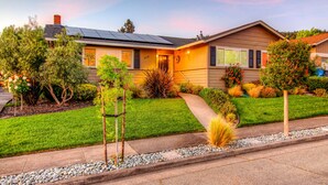 A two-story house with a well-maintained lawn, a pathway leading to the front door, and a small garden area with various plants and shrubs. - Perfect for Wine Country Vacation Living and Entertaining (Santa Rosa)