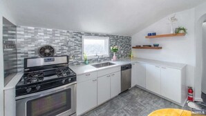 A modern kitchen with a gas stove, dishwasher, and a window with a view. - Cozy & Quiet 2 Bed Apt 20 Minutes to NYC (Fort Lee)