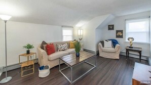 A spacious living room with a high ceiling, two sofas, a coffee table, and a floor lamp. - Cozy & Quiet 2 Bed Apt 20 Minutes to NYC (Fort Lee)