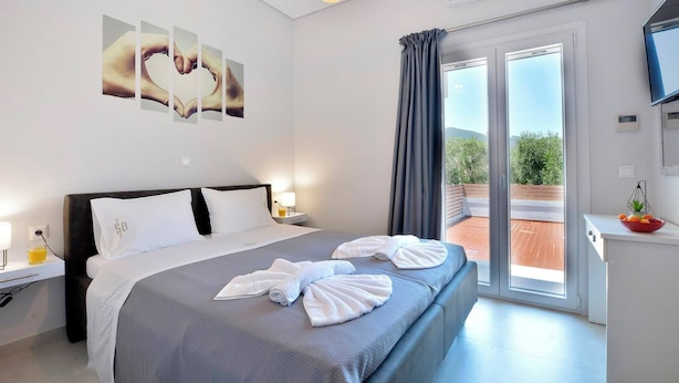A modern hotel room with a large bed, a flat-screen TV, and a balcony with a view of the outdoors. - Villa Ventus Sleeps 7 With Parking (Corfu)