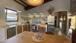 Una cuina moderna amb armaris de fusta, una illa central, llums penjants i vista a les muntanyes per la finestra.