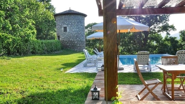 Zona de pati amb piscina, seients de relax i una torre de pedra.