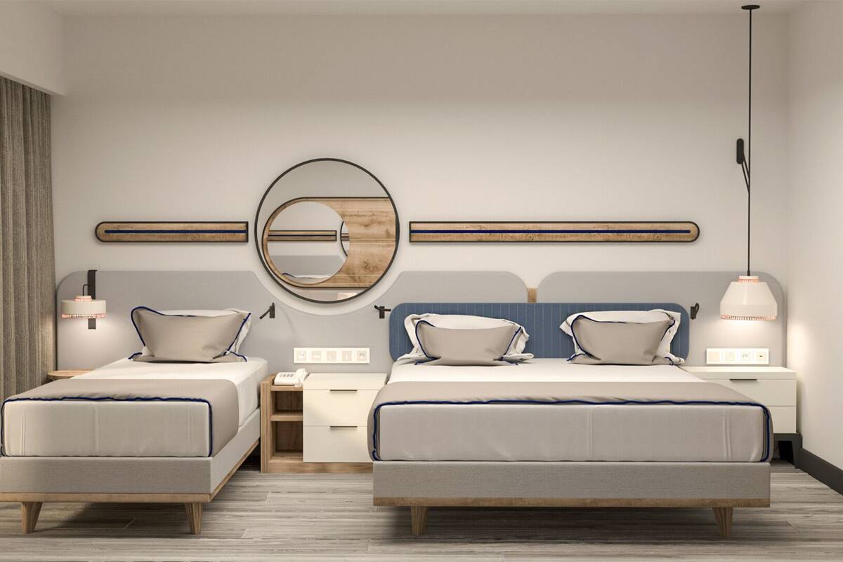 A modern hotel room with two beds, a round mirror, bedside tables, and a desk.