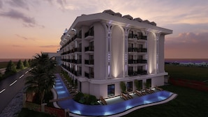 Un hôtel à plusieurs étages doté de balcons, d’une piscine et offrant une vue sur l’océan au coucher du soleil.