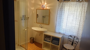 Een douche, handdoeken, zeep, toiletpapier