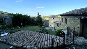 A stone building with a tiled roof, a fenced yard, and a small patio area. - Mas de Saudon (Soyans Auvergne-Rhône-Alpes)