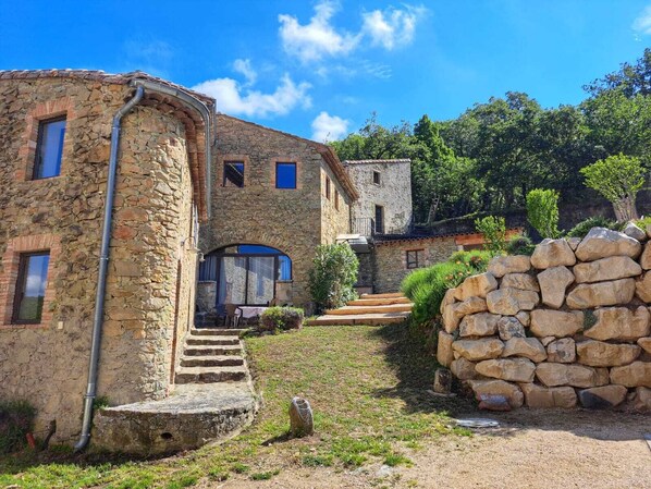 A stone building with a rustic exterior, a set of stone steps leading to a door, and a stone wall in the foreground.