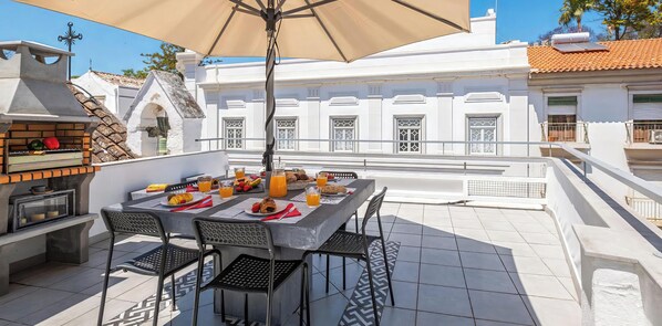 A rooftop terrace with a dining table, chairs, and a grill. - Townhouse with BBQ rooftop in Tavira (Tavira)