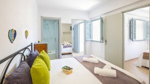 A modern bedroom with a bed, pillows, a bedside table, a mirror, and a bathroom visible through an open door. - Townhouse with BBQ rooftop in Tavira (Tavira)