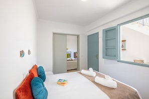 A bedroom with a bed, pillows, a book, towels, a window, and a door. - Townhouse with BBQ rooftop in Tavira (Tavira)