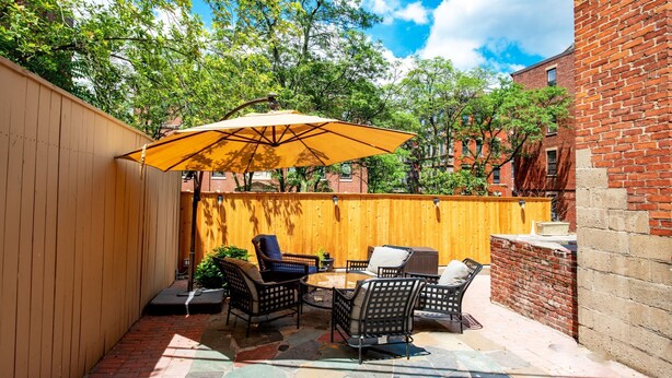 A patio with outdoor furniture, a wooden fence, and a brick wall. - Gorgeous Beacon Hills Studio next to State house (Boston)
