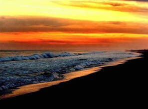 A beach with waves and a sunset.